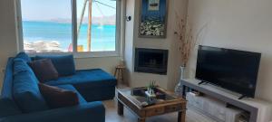 ein Wohnzimmer mit einem blauen Sofa und einem Flachbild-TV in der Unterkunft Mar Azul Σπίτι δίπλα στην παραλία και στο κέντρο! in Elafonisos