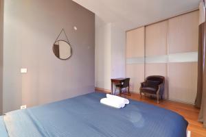 Un dormitorio con una cama azul y una silla. en Appartement Quartier Palais Garnier Free Netflix, en París