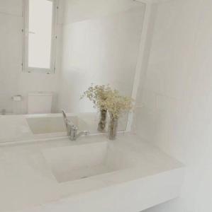 a bathroom sink with a vase with flowers in it at Malujoseignacio in José Ignacio