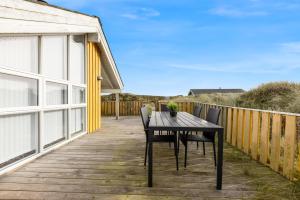 une terrasse en bois avec une table et des chaises dessus dans l'établissement Pool House With Spa And Sauna, 200 Meters From The North Sea, à Frøstrup