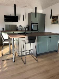 a kitchen with a counter with two chairs and a sink at Randbøldal Camping & Cabins in Randbøl +107 photos