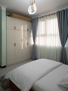 カンパラにあるA home away from homeの大きなベッドと窓のある寝室