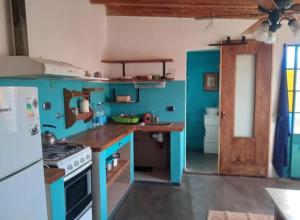 a blue kitchen with a stove and a refrigerator at Cabaña Acacia Mansa 2 in Villa Giardino