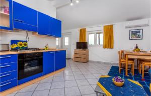 a large kitchen with blue cabinets and a table at Beautiful Apartment In Malinska in Malinska