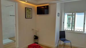 a room with a chair and a television on a wall at Figueira House in Beira Minho in Lisbon