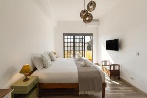 a white bedroom with a bed and a window at Casa do Convento in Óbidos