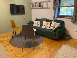 a living room with a green couch and a chair at Szarvas és Bagoly Kalandház in Szarvas