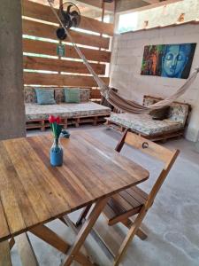a hammock in a room with a wooden table and flowers at Odoyá Casa Hostel in Arraial d'Ajuda