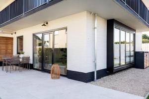 a house with glass doors and a patio at Huswell - Modern Apartment with Garden, Near Beach in Cadzand