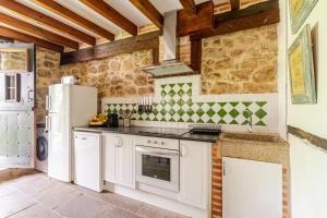 Una cocina con gabinetes blancos y un refrigerador. en Casa de al Lado en Barcenaciones, en Barcenaciones