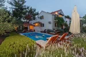 a pool in front of a house with an umbrella at House Sanda in Mirce