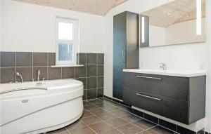 a bathroom with a white tub and a sink at Holiday Home Astavej Løkken in Løkken