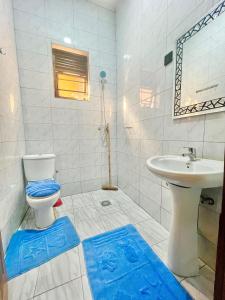 La salle de bains est pourvue de toilettes et d'un lavabo avec des tapis bleus. dans l'établissement Rwanda Guest House Kanombe, Kigali, à Kigali 13 autres photos