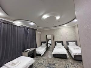 a hotel room with three beds and a mirror at Hotel Shosh Boutique in Tashkent