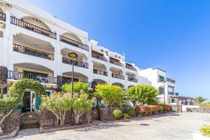 un gran edificio blanco con plantas delante en Rocas del Mar 138, en Costa del Silencio