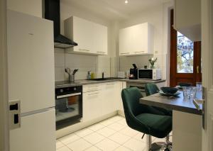 una cucina con mobili bianchi e un tavolo con sedie verdi di Le Shilichic - Gare a Schiltigheim