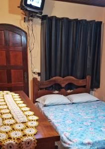 イーリャ・グランデにあるapartamento frente da praiaのベッドとテーブルとテレビのある寝室 +2枚の写真