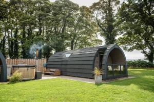 a black shed in a yard with a grill at Eastfield Glamping Farm in Spennithorne