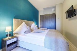 a bedroom with a large white bed with a blue wall at Columbus Suite mit Ostbalkon in Wustrow