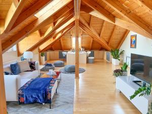 una sala de estar con techos de madera y una habitación con sofá en "GLÜCKSMOMENT" - Premium Apartments Seekirchen, beeindruckende Ferienwohnung mit gemeinsam genutzter Poolarea, en Seekirchen am Wallersee