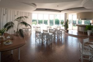 jadalnia ze stołami, krzesłami i oknami w obiekcie Hotel La Conchiglia w mieście Fregene