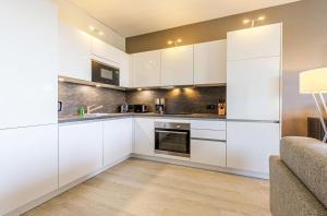 a kitchen with white cabinets and a couch at Dünenquartier - 3 Obergeschoss mit Ostseeblick - 600m zum Strand in Wustrow