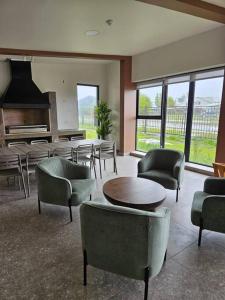 Una sala de estar con sillas y mesas y un piano. en Depto Mirador del Fiordo, en Puerto Natales
