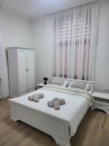 ein weißes Schlafzimmer mit einem großen weißen Bett mit zwei Kissen in der Unterkunft Guest House Eleni in Balş