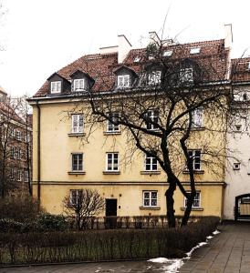 a large yellow building with a tree in front of it at Old Town Warsaw Joanna's Apartments in Warsaw