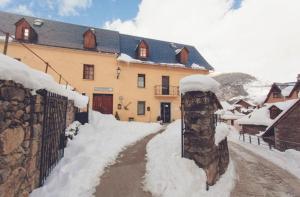 a house with a fence and snow on it at Petit Verneda in Casau