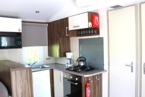 a small kitchen with wooden cabinets and a stove at Camping Tucan - Mobile Homes by Lifestyle Holidays in Lloret de Mar