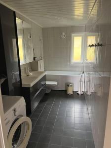 a bathroom with a tub and a toilet and a sink at Nydelig villa med havutsikt og utendørs badestamp in Botnhamn