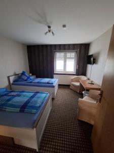 a hotel room with two beds and a couch at Pension Zum Römer in Gräfentonna +3 photos
