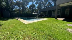 a backyard with a swimming pool in the grass at Musas con Pileta NO ACEPTO GRUPO DE JOVENES in Pinamar