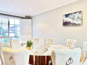 a white dining room with a marble table and white chairs at Villa pool garden in Melbourne +17 photos