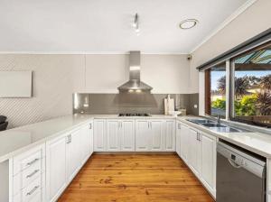 a kitchen with white cabinets and a large window at Villa pool garden in Melbourne