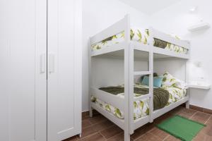 a white bunk bed in a room with a green rug at Home2Book Cozy Beachfront Getaway in Tarajalejo in Tarajalejo