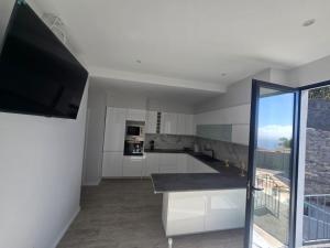 a kitchen with white cabinets and a flat screen tv at Ocean Paradise de Santa Luzia in Funchal