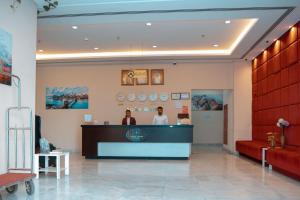 two people standing at a counter in a lobby at Aspire Tower - One Bedroom Sleek Suite in Manama