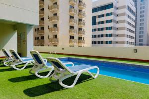a row of chaise lounge chairs next to a swimming pool at Aspire Tower - One Bedroom Sleek Suite in Manama