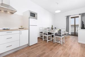 a kitchen with white cabinets and a table with chairs at Home2Book Cozy Beachfront Getaway in Tarajalejo in Tarajalejo