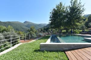 a swimming pool in a yard with mountains in the background at Feel Discovery Casa da Pedra in Arouca