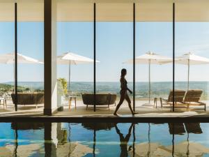 a woman walking by a pool in a building at Royal Champagne Hotel & Spa in Champillon