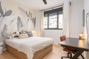 a bedroom with a bed with a desk and a wall mural at Live It Malaga in Málaga