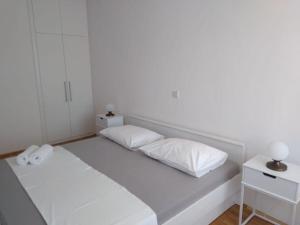 a white room with a bed with two pillows at Apartments and Rooms Ref in Sumartin