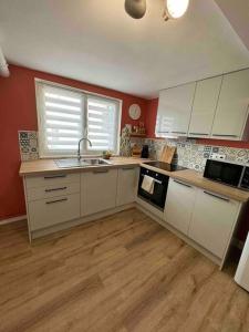 a kitchen with white cabinets and a sink and a window at Appart centre ville in La Loupe +16 photos