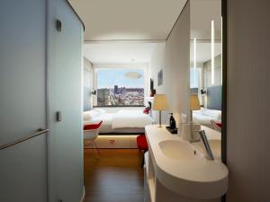 a bathroom with a sink and a bedroom with a bed at citizenM New York Bowery in New York