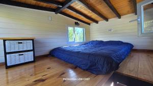 una camera con un letto in una stanza con pavimenti in legno di Tiny House El Barco a El Hoyo