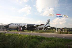 un avión estacionado al lado de una carretera con banderas en Vliegtuigsuite Teuge en Teuge