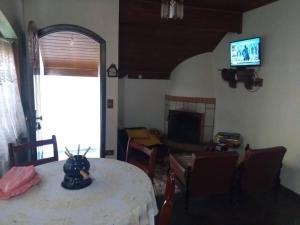 un soggiorno con un tavolo e una televisione di Casa Vivenda dos Bem-te-vis a Monte Verde